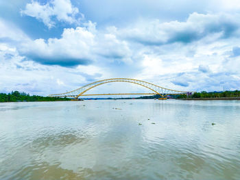 Arch bridge over river against sky