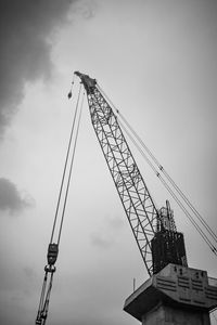 Low angle view of crane at construction site against sky