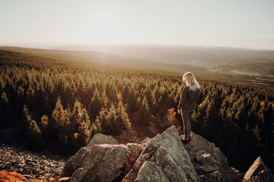 Man standing on rock against sky