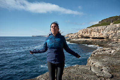 Fitness woman in sports set training with elastic band,weights gym exercises, in front of the water	