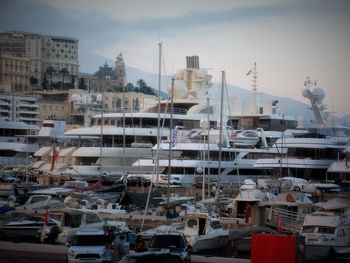 Sailboats moored on harbor against buildings in city