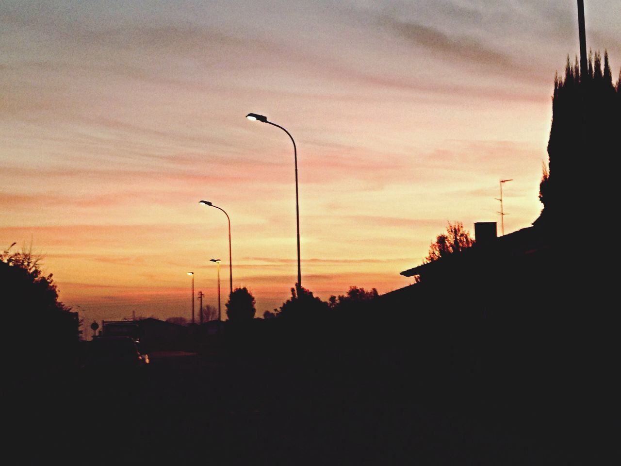 sunset, silhouette, street light, sky, orange color, lighting equipment, built structure, transportation, architecture, tree, building exterior, dusk, cloud - sky, car, nature, scenics, beauty in nature, outdoors, street, road