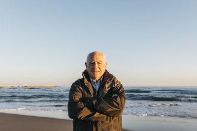 Young man standing at beach against clear sky