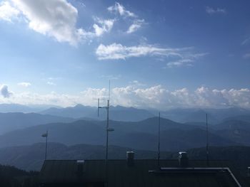 Antenna on rooftop of house against mountain range