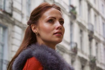 Close-up of young woman looking away in city