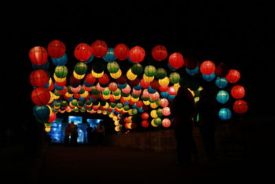 Multi colored balloons against illuminated lights at night