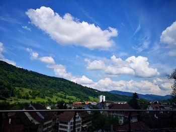 Scenic view of town by mountain against sky