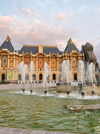 Fountain in lake against buildings