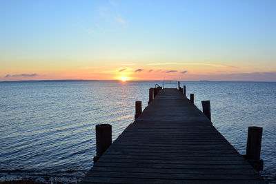 Pier over sea against clear sky during sunset