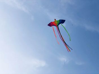 Low angle view of colorful kite flying against blue sky