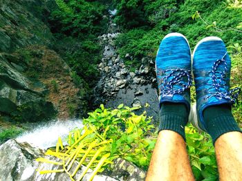 Low section of man sitting by waterfall