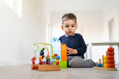 Cute boy sitting on toy at home