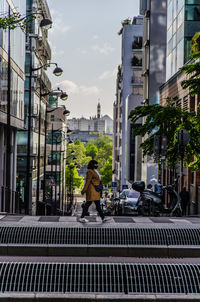 Woman walking on street against buildings in city