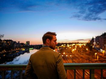 Man looking at city against sky during sunset