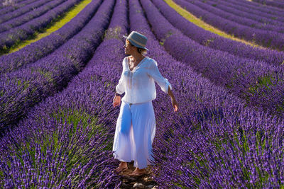 Woman standing by purple flower on field