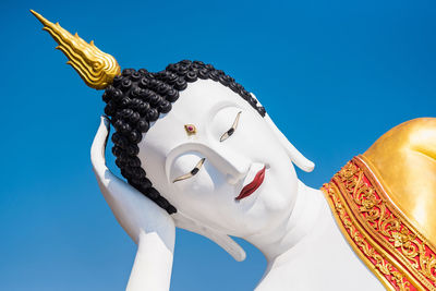 Low angle view of statue against temple against blue sky