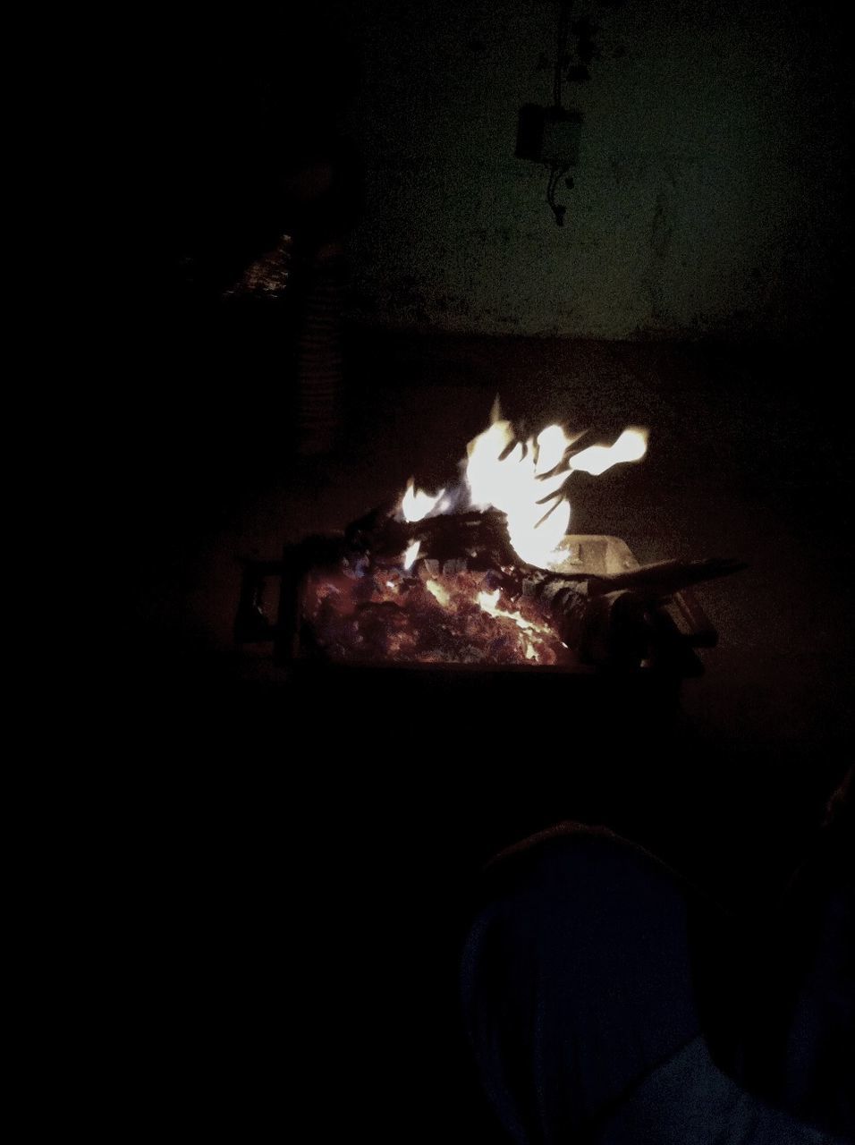 indoors, dark, burning, flame, high angle view, fire - natural phenomenon, night, illuminated, close-up, heat - temperature, shoe, light - natural phenomenon, one person, wall - building feature, darkroom, glowing, home interior, shadow, messy, still life