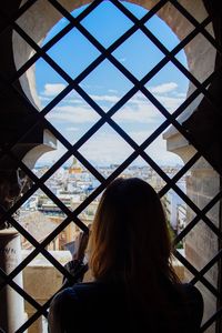 Rear view of woman looking through window