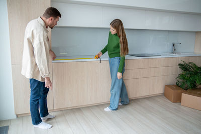 Concentrated family couple man woman measuring surface on new kitchen cabinets relocation
