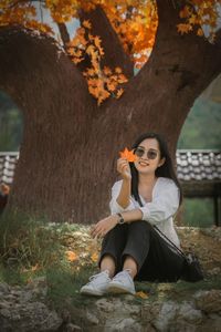 Young woman sitting on tree trunk