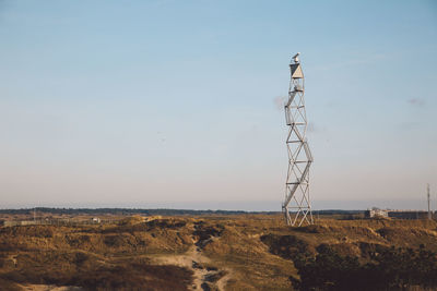 Communications tower on landscape against sky