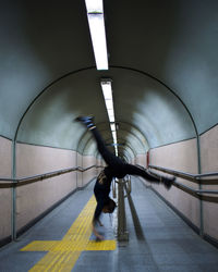 Side view of woman practicing handstand at subway station