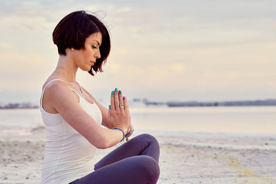 Woman mediating while sitting at beach