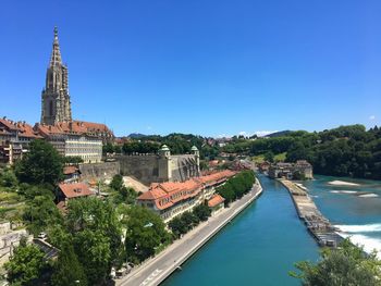 Buildings by swimming pool in city against clear blue sky