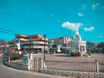 Road by buildings against blue sky