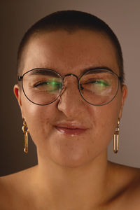 A swarthy girl with short hair and freckles in glasses grimaces and wrinkles the nose.