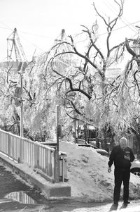 Rear view of man standing by railing during winter