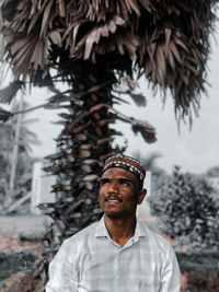 Portrait of young man standing against plants