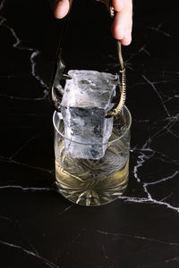 Close-up of hand holding container against black background