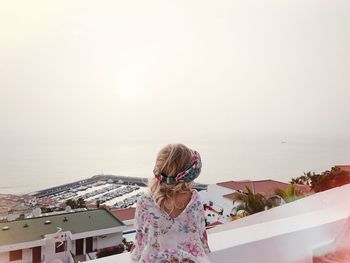 Rear view of girl standing by sea against clear sky