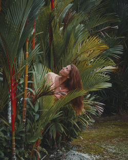 Portrait of young woman with palm tree