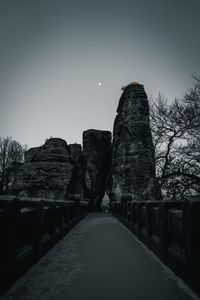 Walkway amidst trees against clear sky at dusk