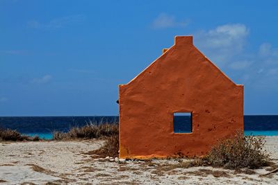Built structure on beach by sea against sky