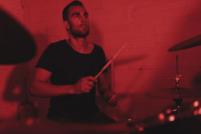 Group of musicians playing in red neon lights at music studio