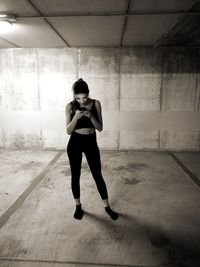 Woman using smart phone while standing against wall