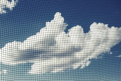 Low angle view of cloudy sky seen through netting