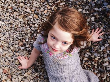 Portrait of cute girl lying on pebbles