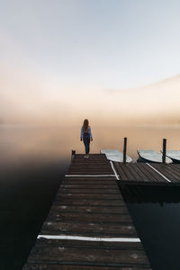 Young traveler female relaxing on the wooden pier near the lake,and watching the foggy sunrise