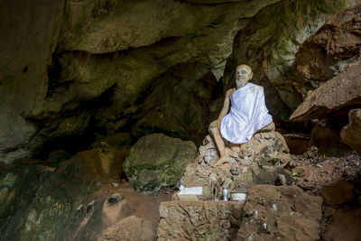 Rear view of woman sitting on rock