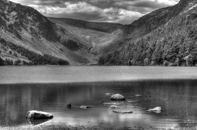 Scenic view of lake and mountains against cloudy sky