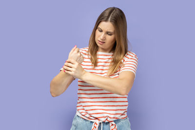 Portrait of young woman standing against blue background