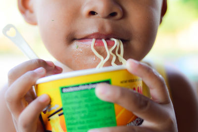Close-up portrait of boy holding instant noodles cup