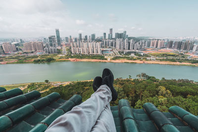 Crop tourist on rooftop with cityscape