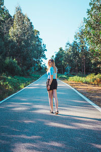 Full length portrait of young woman on road