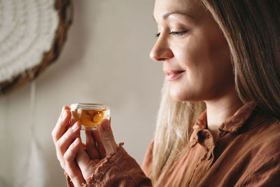 Close-up of young woman drinking tea from small cup