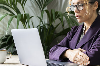 Young woman using laptop while sitting on table